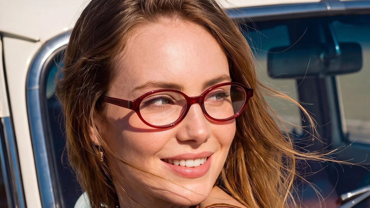 Woman wearing red oval acetate glasses outdoors next to a vintage car