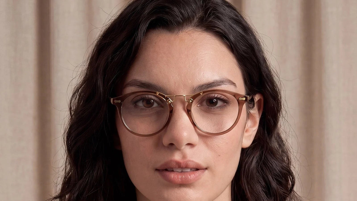 Woman wearing tortoise round eyeglasses with a gold bridge, looking at the camera