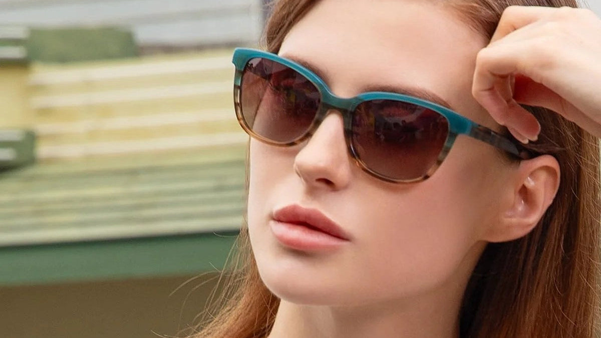 Woman wearing teal and tortoise sunglasses outdoors on a sunny holiday day