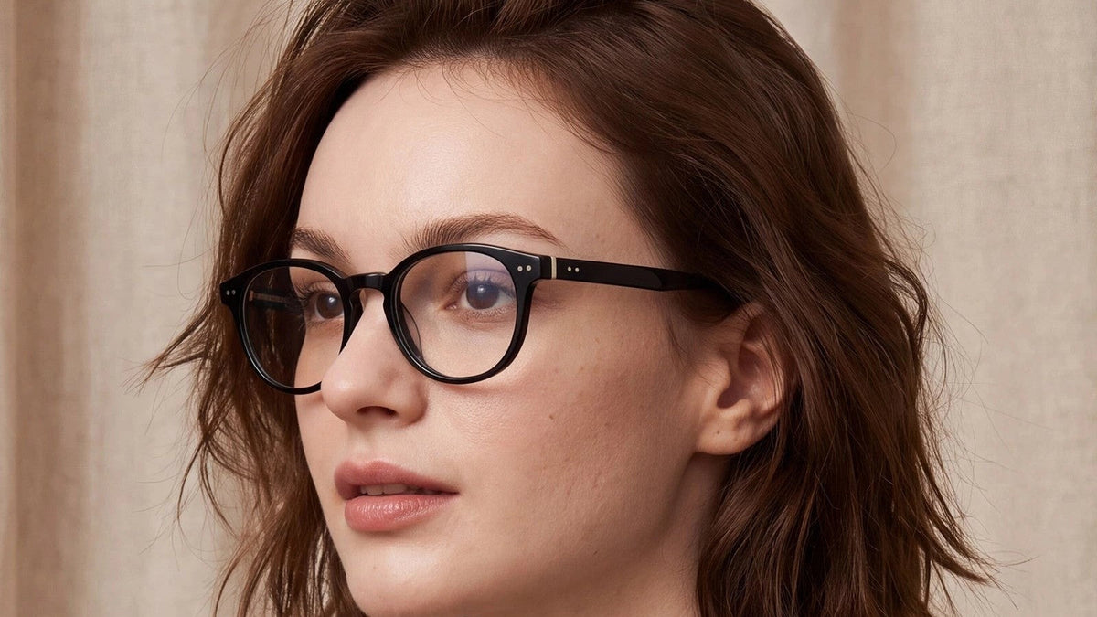 Woman in round black prescription glasses against a linen curtain