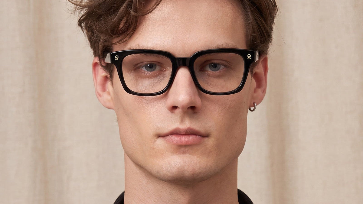 Man wearing black acetate prescription glasses against a linen backdrop