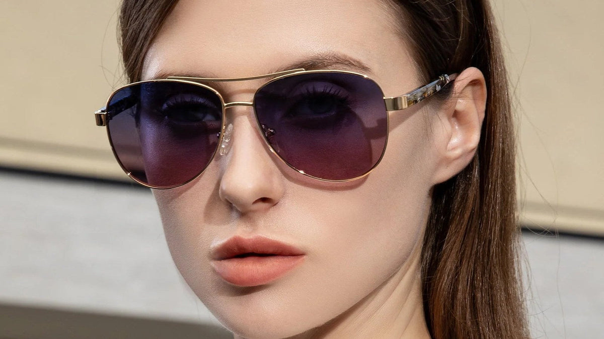 Woman wearing gold aviator sunglasses with gradient purple lenses