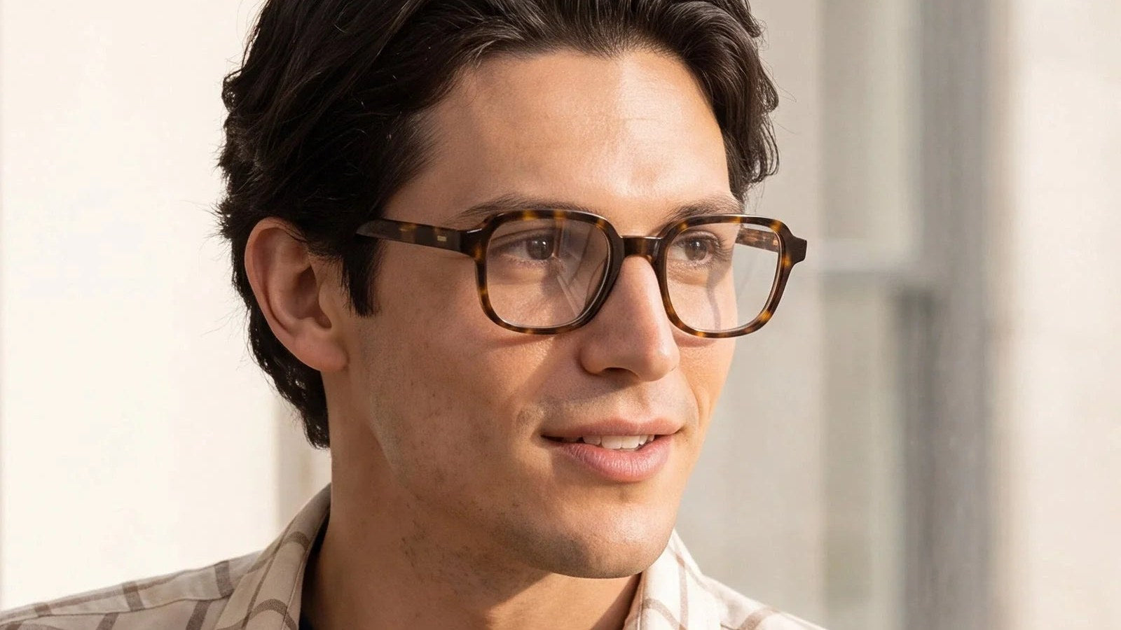 Man wearing tortoise rectangle acetate eyeglasses by a sunny window