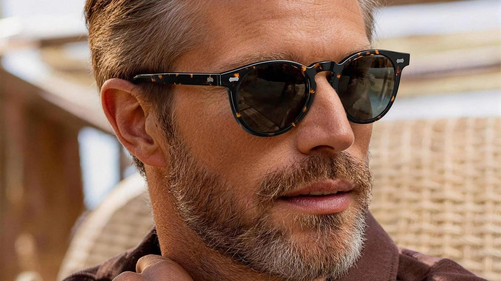 Man wearing tortoiseshell round sunglasses with dark lenses outdoors