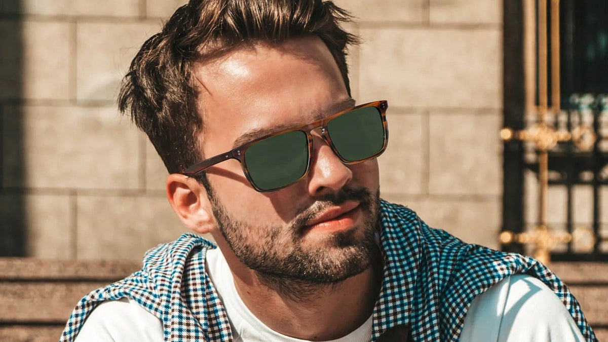 Man wearing rectangle tortoise sunglasses with green lenses on city steps