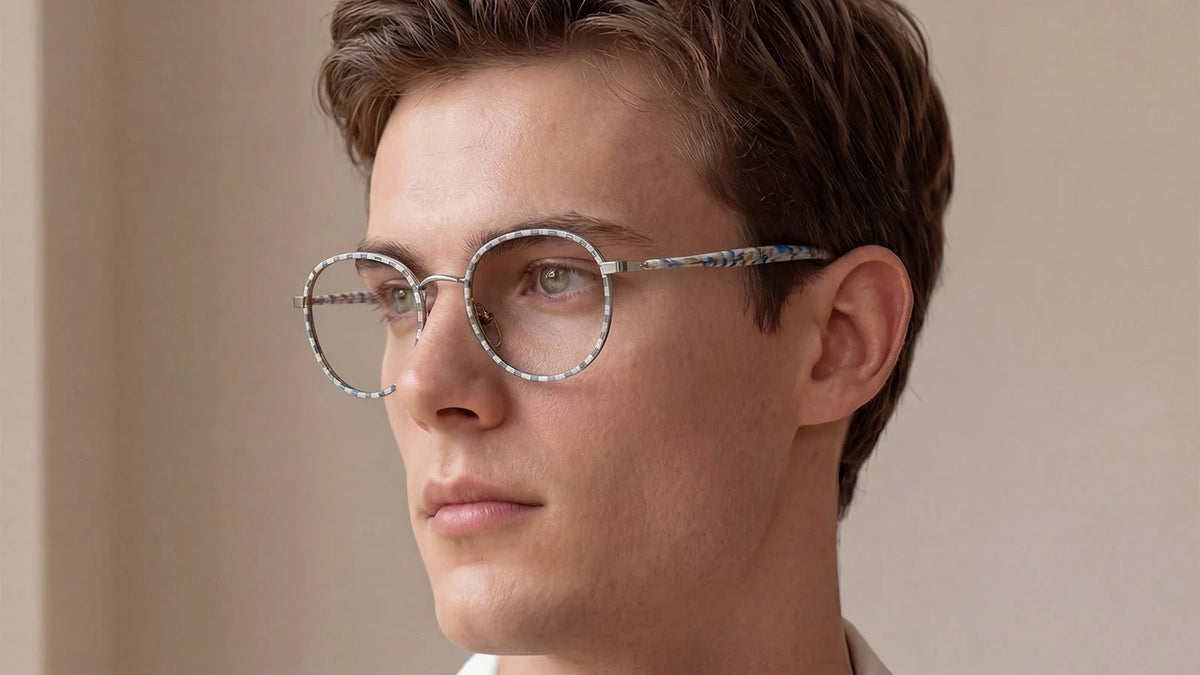Man wearing round two-tone glasses with a beige and blue patterned rim and metal bridge